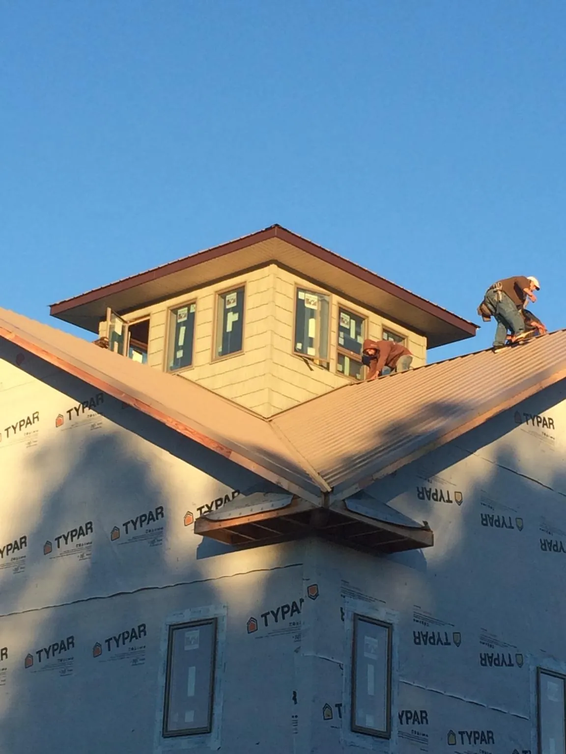 Roofers working around a rooftop cupola on a new metal roof at sunset — Roof Waterproofing in Auburn by Roofing Brothers